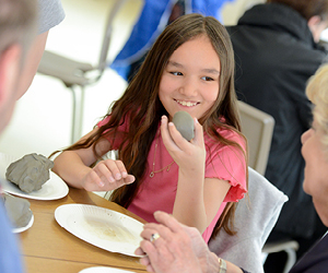 A young girl who is scultping with clay